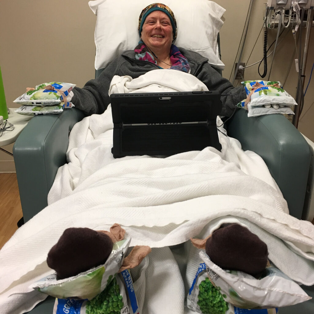 Ellen in hospital bed with frozen peas on hands and feet